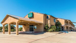 A Quality Inn with a covered entrance, a parking lot, and a clear blue sky.