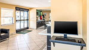 Eine Hotelhalle mit Rezeption, Computereinrichtung, einer Sitzecke und Blick auf Küche und Speisesaal.