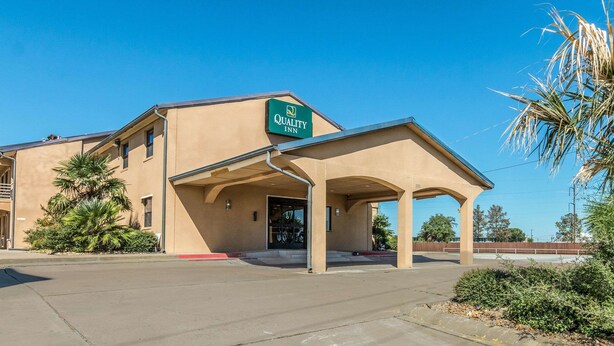 A Quality Inn with a covered entrance, beige exterior, and palm trees nearby.