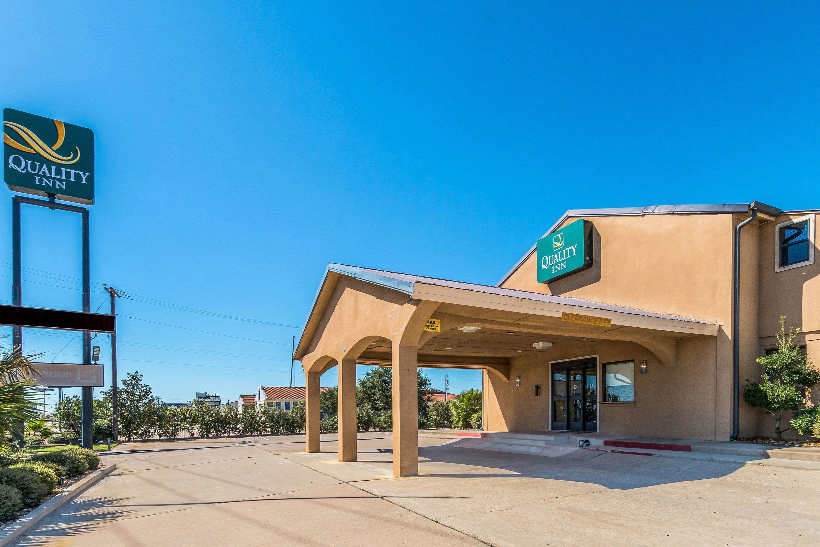 A Quality Inn hotel with a covered entrance and a clear blue sky.