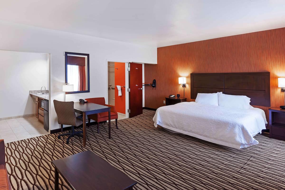 Una habitación de hotel con una cama grande, un escritorio, una silla y una mesita.