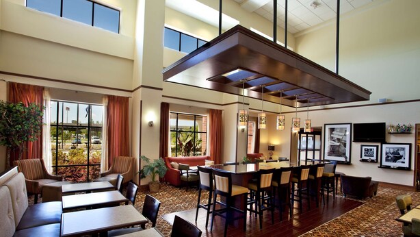 A hotel lobby with a central bar area, seating arrangements, and a patterned carpet. - Hampton Inn & Suites Morgan City (Morgan City)