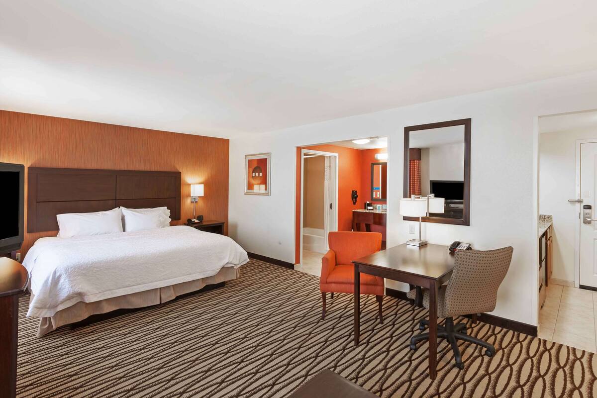 Una habitación de hotel con cama, escritorio, silla y televisión.