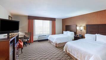 A hotel room with two beds, a TV, a desk, and a chair.