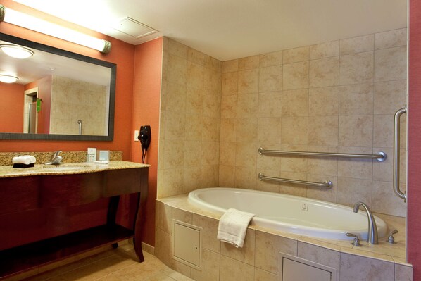 A modern bathroom with a large bathtub, a vanity with a mirror, and a towel rack. - Hampton Inn & Suites Morgan City (Morgan City)