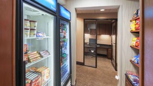 A hotel lobby with a refrigerator stocked with snacks and beverages, a reception desk, and a view into the dining area. - Hampton Inn & Suites Morgan City (Morgan City)