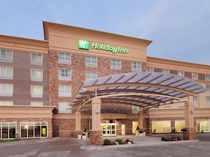 A Holiday Inn hotel with a brick facade, a covered entrance, and a clear sky.
