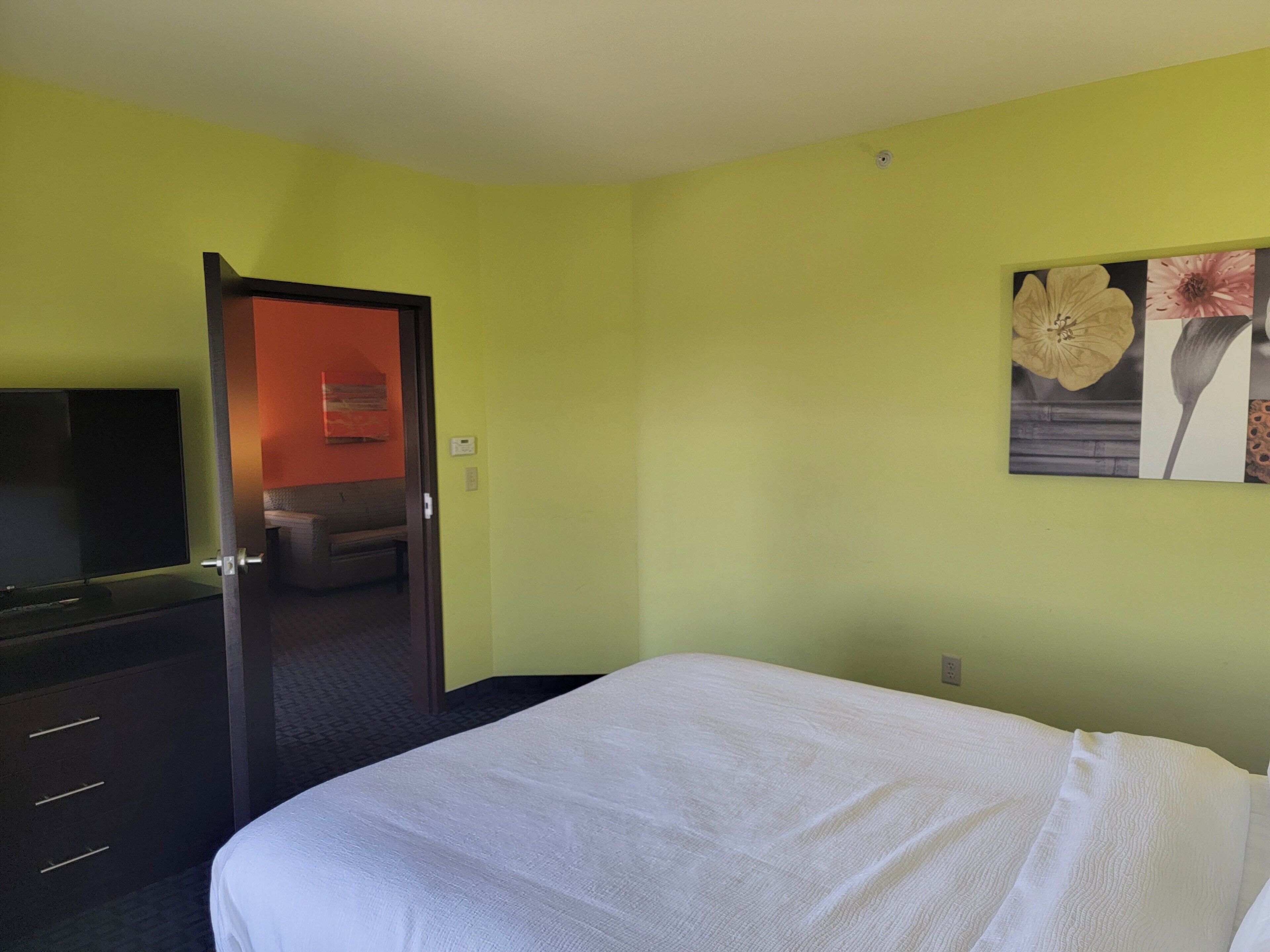 Une chambre d’hôtel comprenant un lit, une télévision, un bureau et une porte donnant accès à une salle de bain.