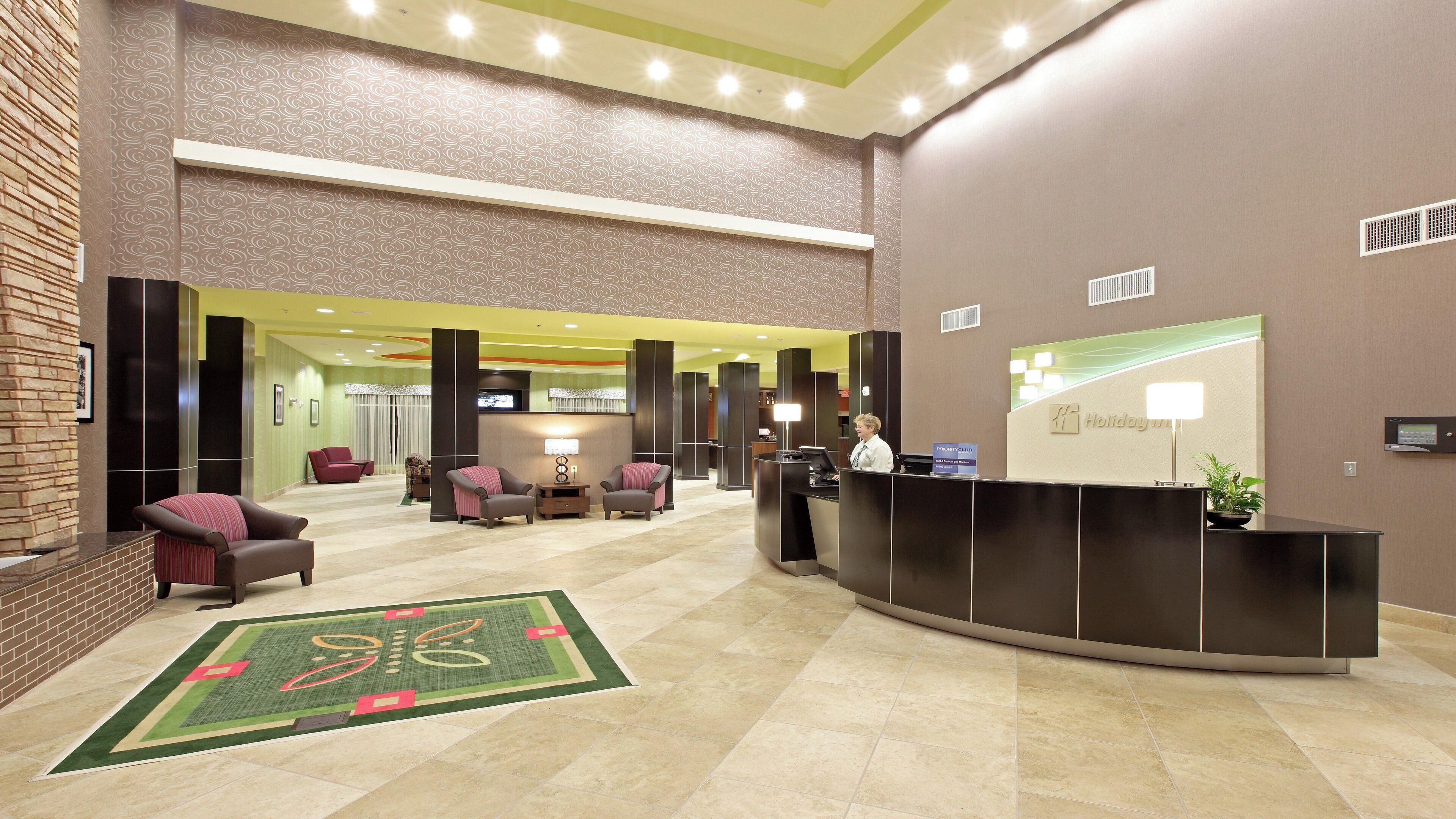 Um saguão de hotel com balcão de recepção, área de estar e um espelho grande.