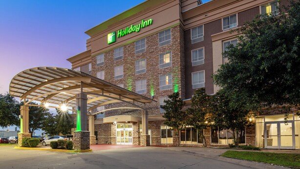 A Holiday Inn hotel with a brick facade, a covered entrance, and a parking lot. - Holiday Inn Garland by IHG (Garland)