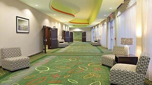 A hotel corridor with patterned carpet, seating areas, and a green wall with a framed picture. - Holiday Inn Garland by IHG (Garland)