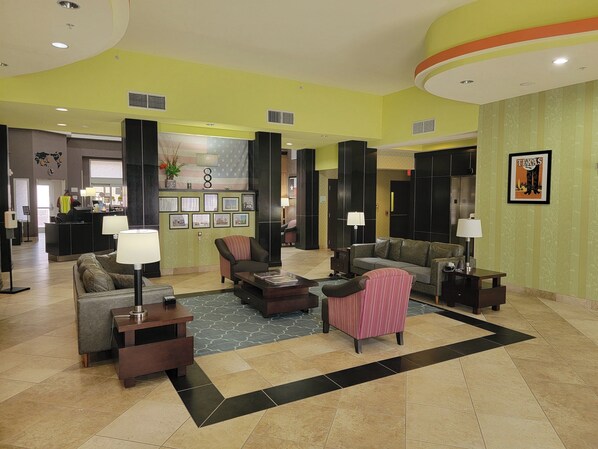A spacious lobby with a reception desk, multiple seating areas, and a large American flag. - Holiday Inn Garland by IHG (Garland)