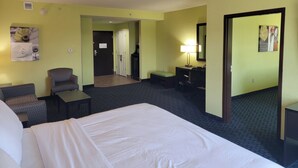 A hotel room with a bed, a desk, a chair, a small table, a lamp, and a mirror. - Holiday Inn Garland by IHG (Garland)