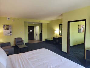 A hotel room with a bed, a desk, a chair, a small table, a lamp, and a mirror. - Holiday Inn Garland by IHG (Garland)