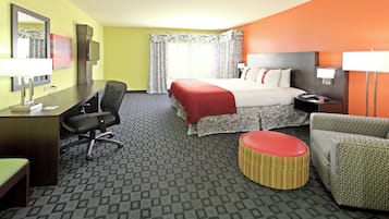 A hotel room with a bed, desk, chair, and ottoman.