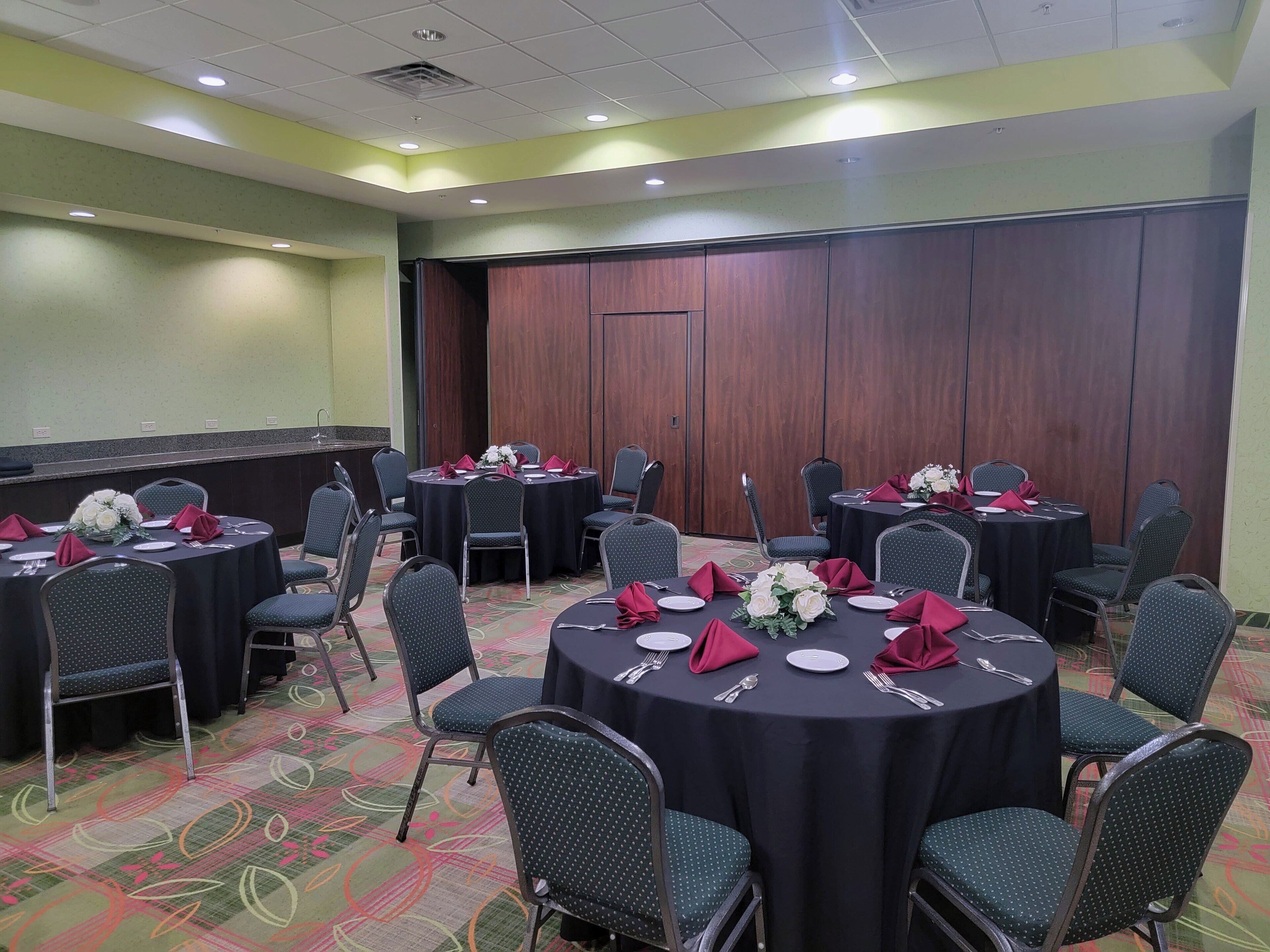 A conference room with round tables, chairs, and floral centerpieces.