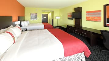 A hotel room with two beds, a desk, a chair, a television, and artwork on the walls.