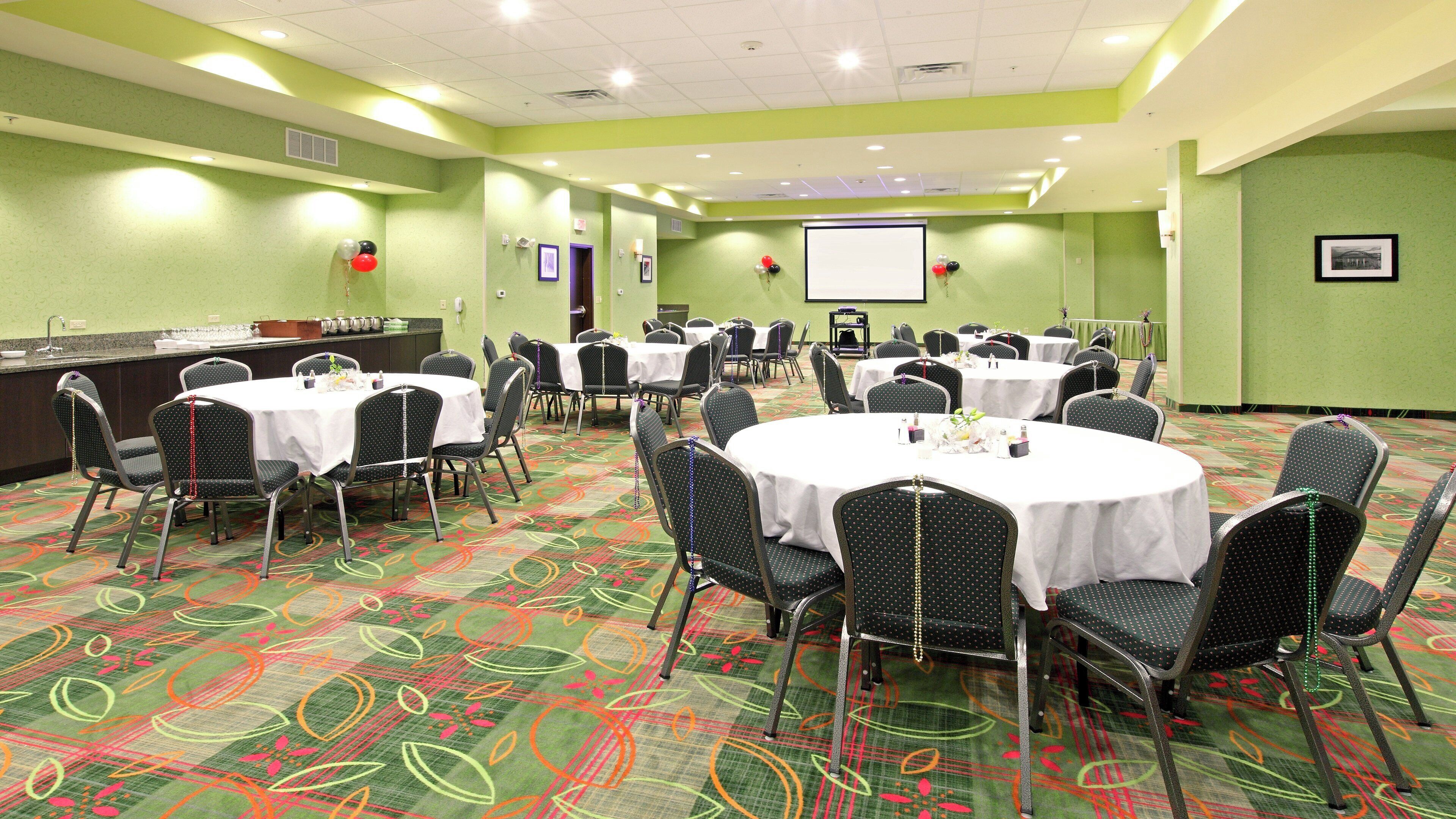 A conference room with round tables, chairs, and a projection screen.