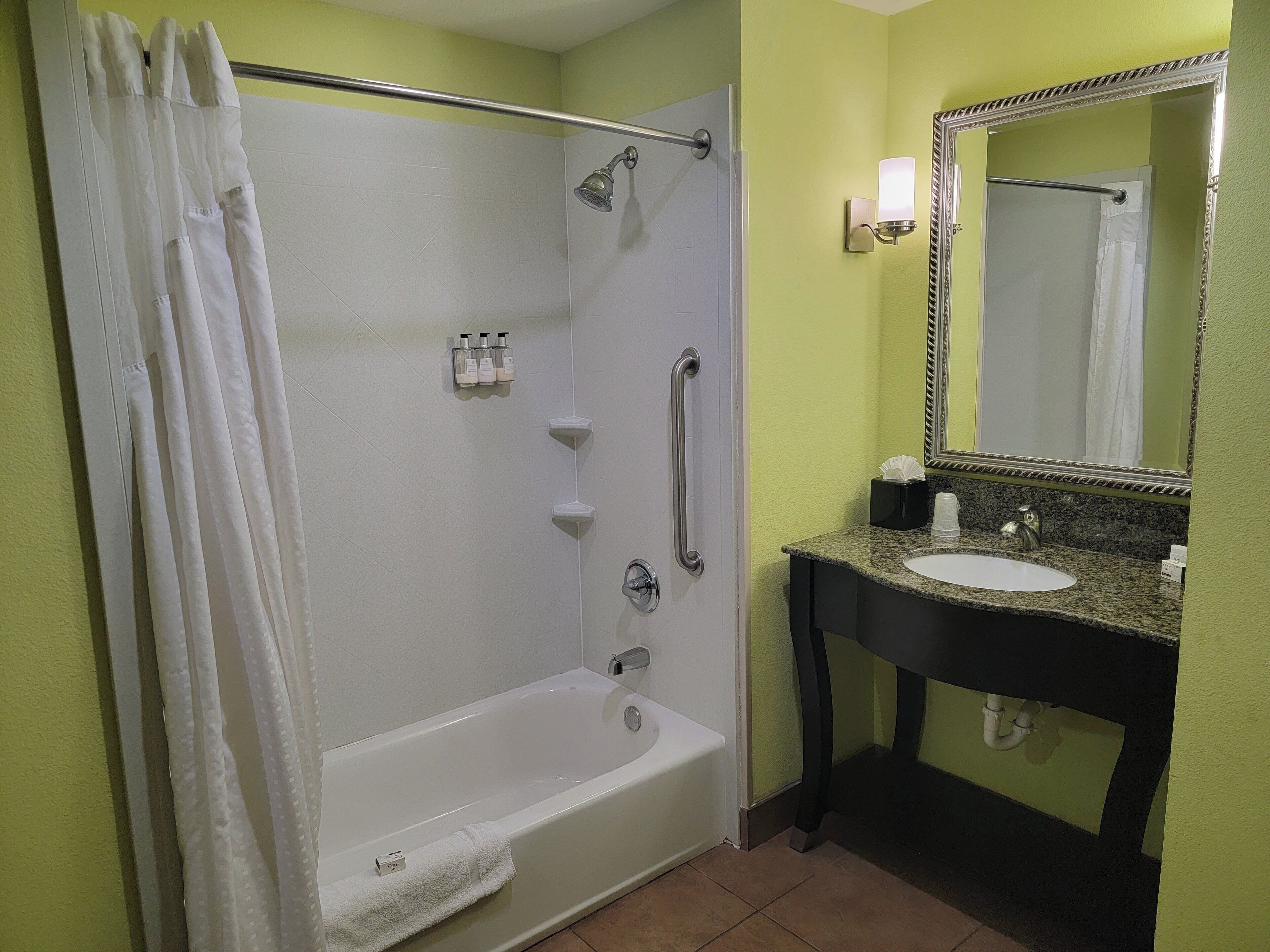 A bathroom with a bathtub, a shower, a sink, and a mirror.