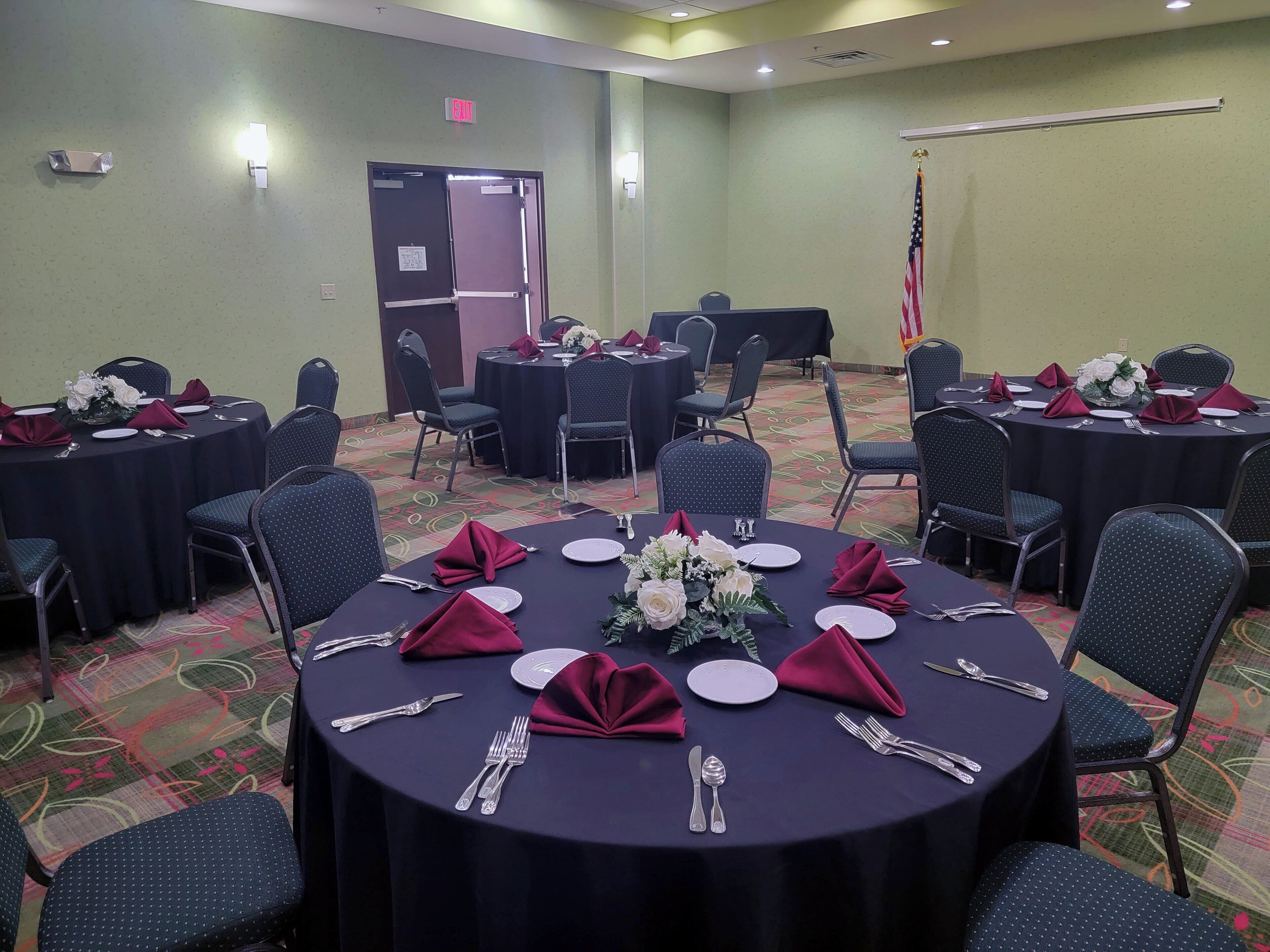A conference room with round tables, chairs, and a flag.