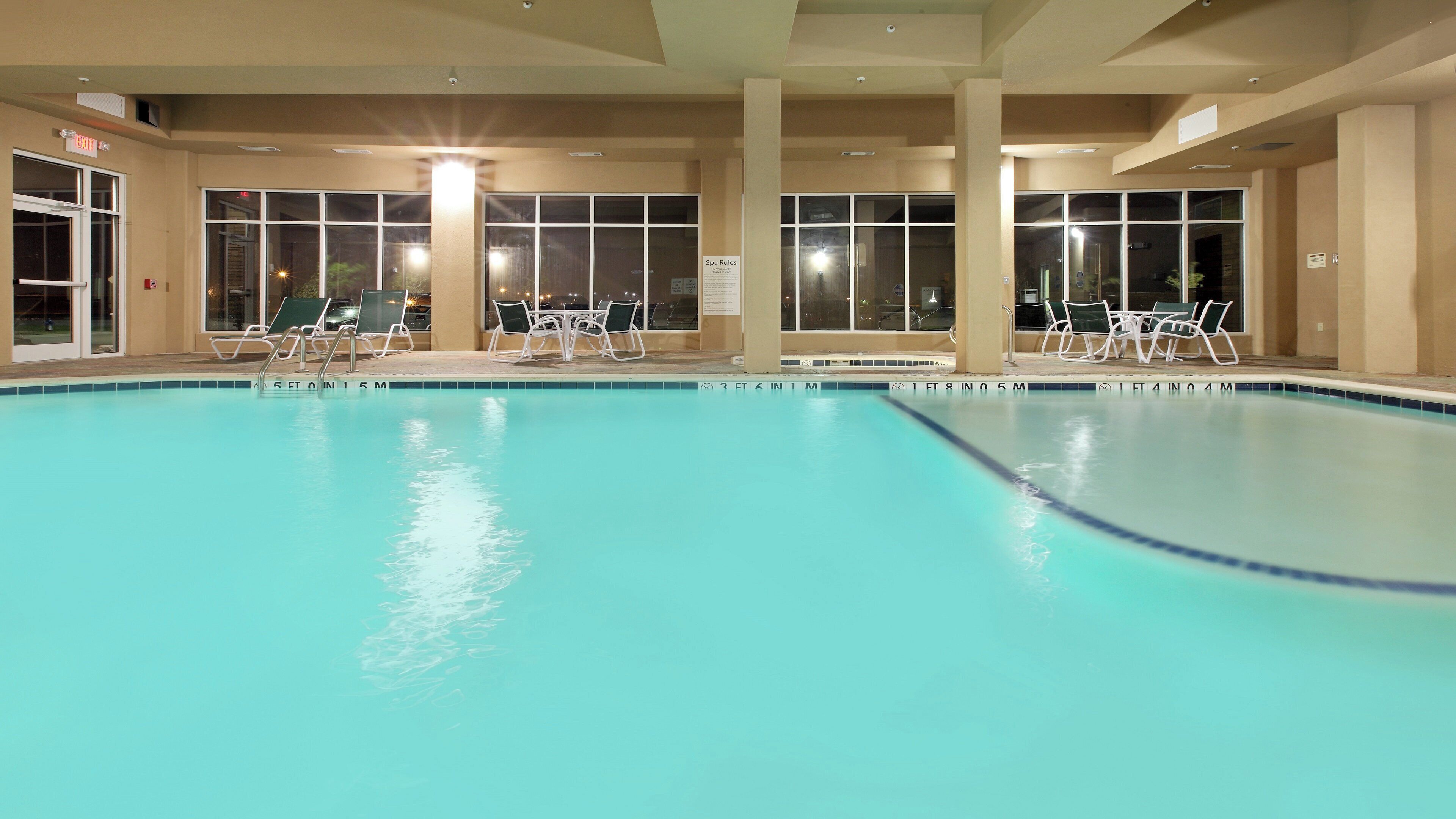 Une piscine intérieure à l’eau claire, entourée de chaises longues et agrémentée d’un panneau indiquant les règles du centre de bien-être.