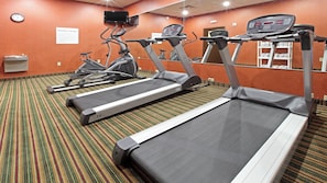 A fitness center with treadmills, stationary bikes, and a wall clock.