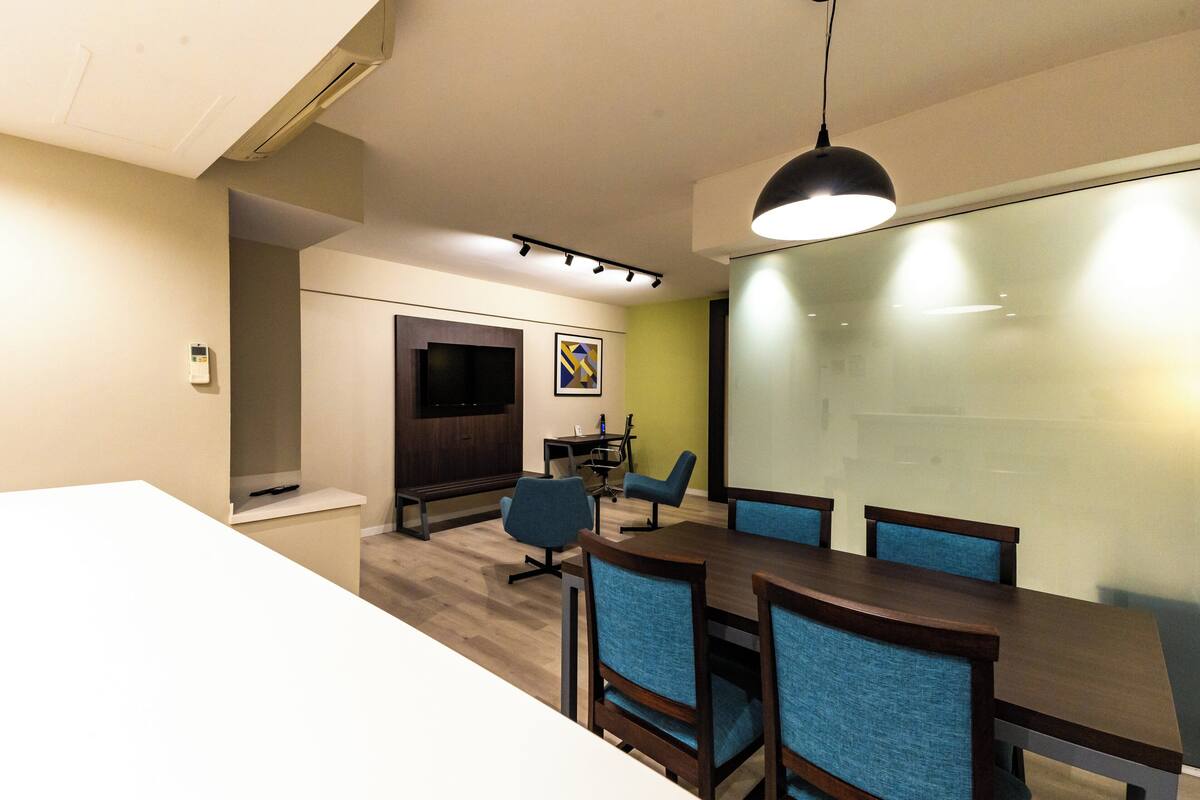A conference room with a long table, blue chairs, a projector screen, and a whiteboard.