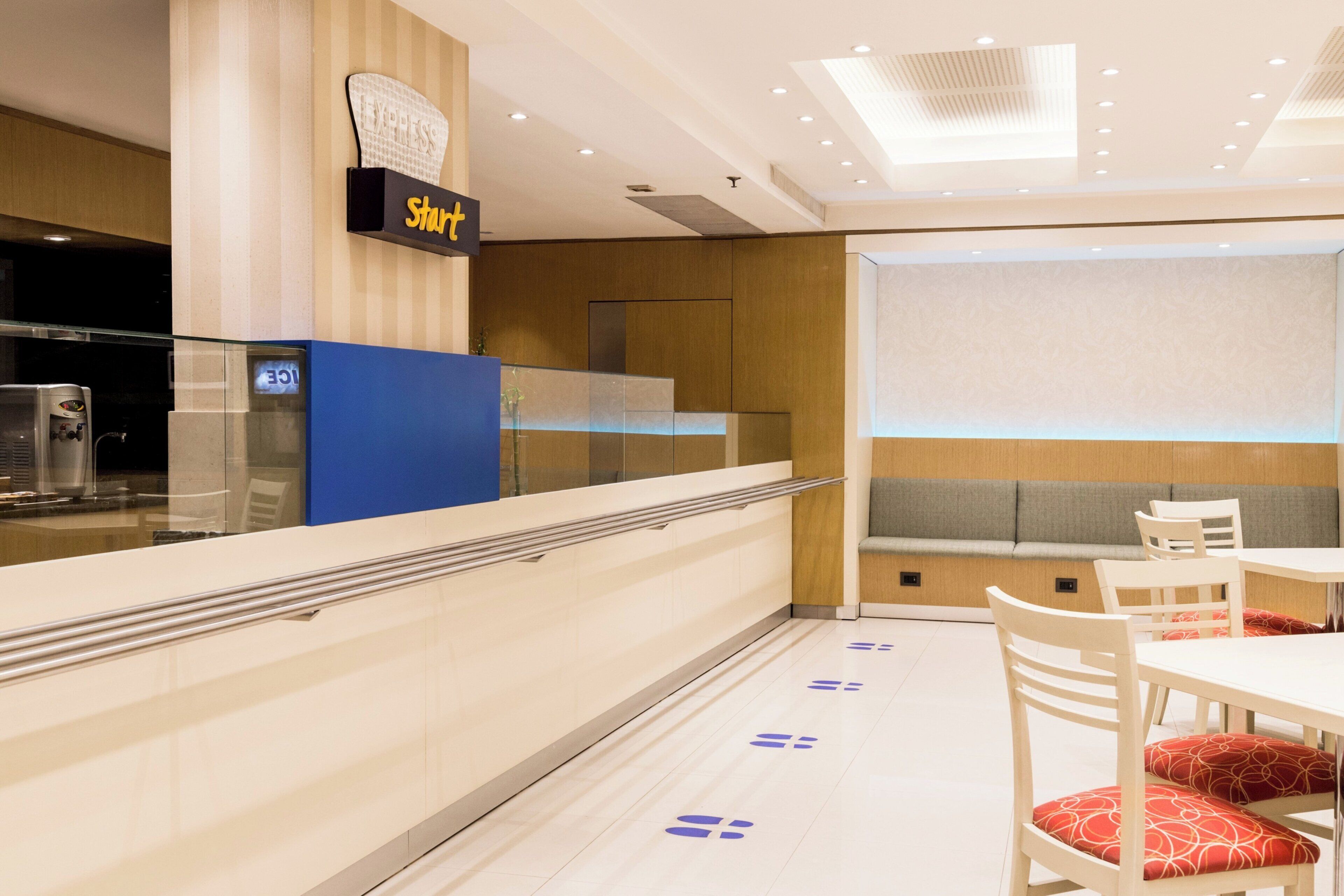 Un vestíbulo de hotel con mostrador de recepción, zona de estar y una pantalla de proyección.