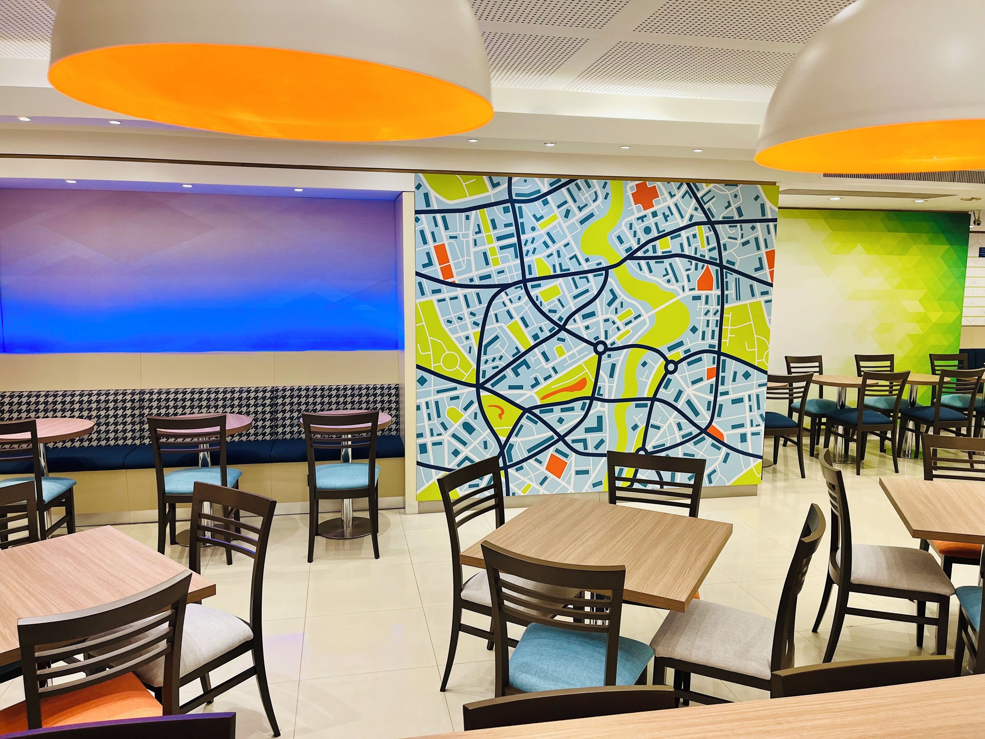 Ein Restaurant mit modernem Interieur, das Sitzmöbel mit Hounds-Tooth-Muster, eine große Wandkarte und eine blaue Akzentwand zeigt.