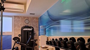 A gym with exercise equipment, a water dispenser, and a clock on the wall. - Holiday Inn Express Rosario by IHG (Rosario)