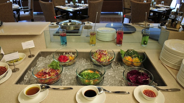 Una mesa de buffet con ensaladas y bebidas variadas.