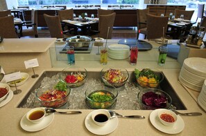 A buffet setup with various salads and beverages. - Cambay Grand (Ahmedabad)