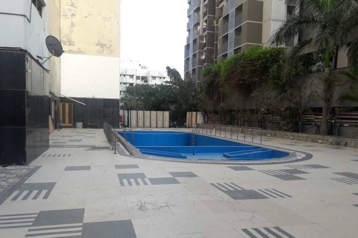 Ein Schwimmbecken mit blauer Innenausstattung, umgeben von einer mit geometrischen Mustern versehenen Fliesenfläche.