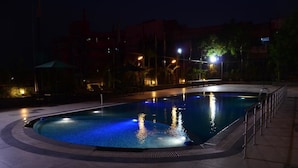 Una piscina iluminada con luz ambiental y un deck circundante.