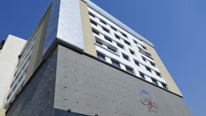 Un edificio alto con un diseño arquitectónico moderno, que combina vidrio y hormigón.