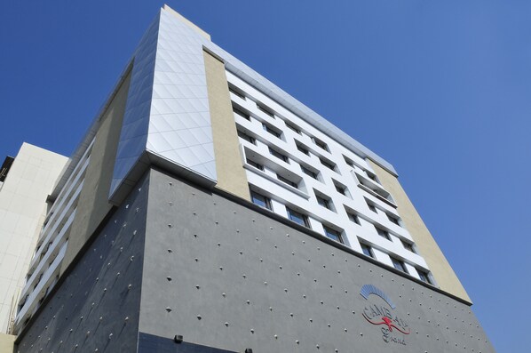 A tall building with a modern architectural design, featuring a mix of glass and concrete materials. - Cambay Grand (Ahmedabad)