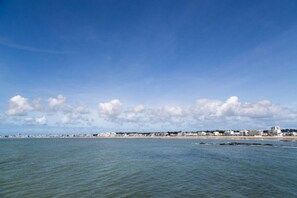 A coastal view with a beach and buildings in the distance under a clear sky. -  The Originals City, Hôtel Anaïade, Saint-Nazaire-Pornichet (Saint-Nazaire)