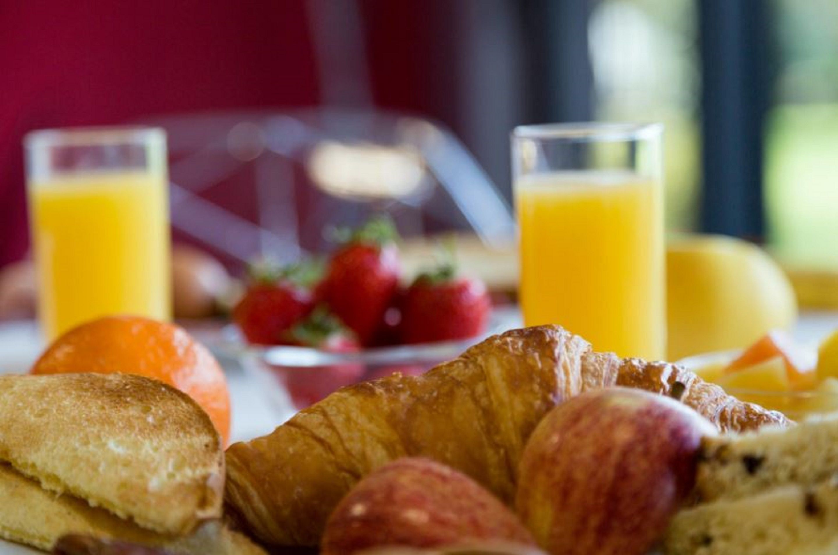 Desayuno con cruasanes, fresas y vasos de zumo de naranja.