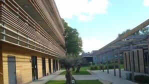 A modern building with a wooden facade and a covered outdoor area with seating. -  The Originals City, Hôtel Anaïade, Saint-Nazaire-Pornichet (Saint-Nazaire)