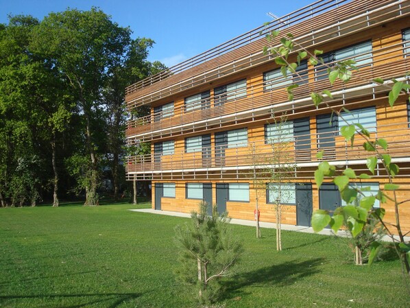 A modern building with a flat roof, multiple windows, and a wooden facade. -  The Originals City, Hôtel Anaïade, Saint-Nazaire-Pornichet (Saint-Nazaire)