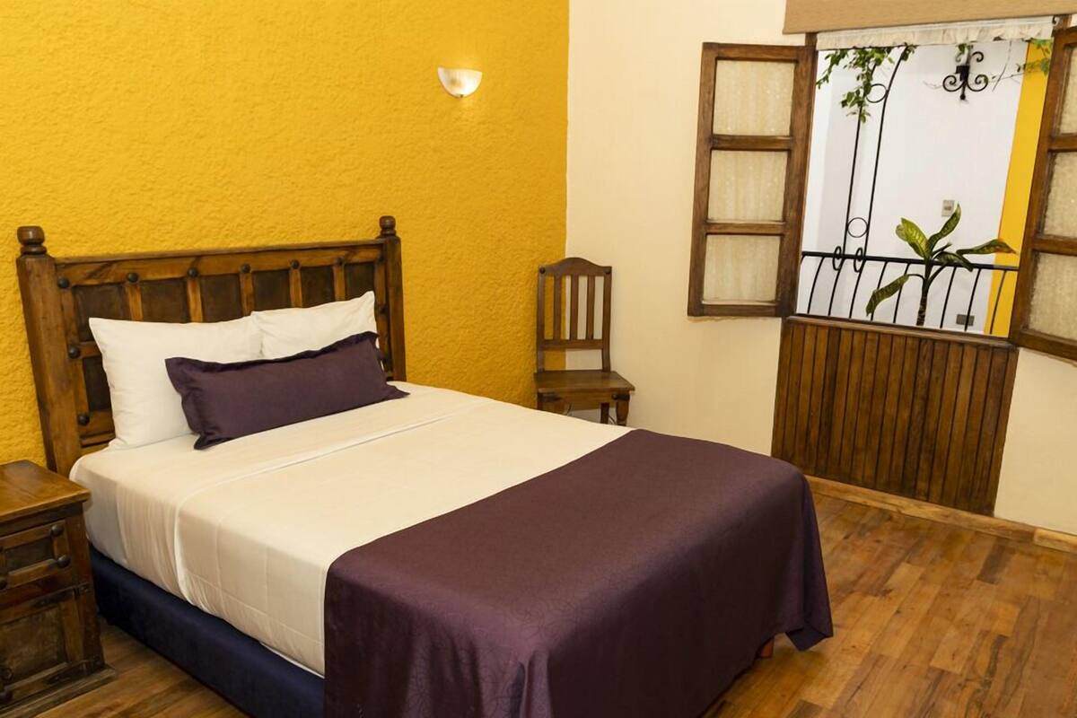 A bed with a wooden headboard, a nightstand, and a window with a view of a balcony.