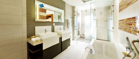 A modern bathroom with two sinks, a large bathtub, and a glass-enclosed shower area.
