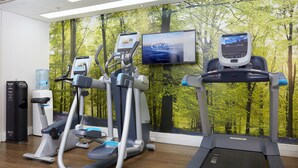 Un gimnasio con cintas de correr, elípticas y un dispensador de agua.