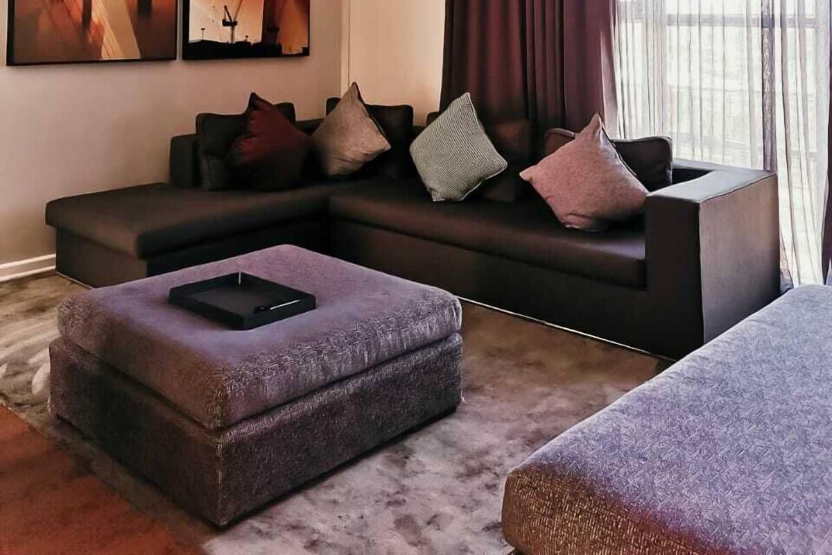 Een moderne woonkamer met een modulaire bank, een salontafel en een groot raam met dunne gordijnen.