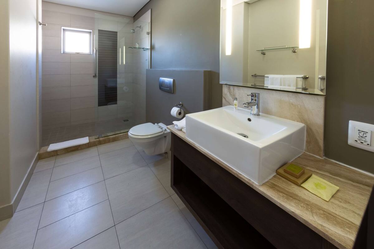 Een moderne badkamer met toilet, wastafel en douche.