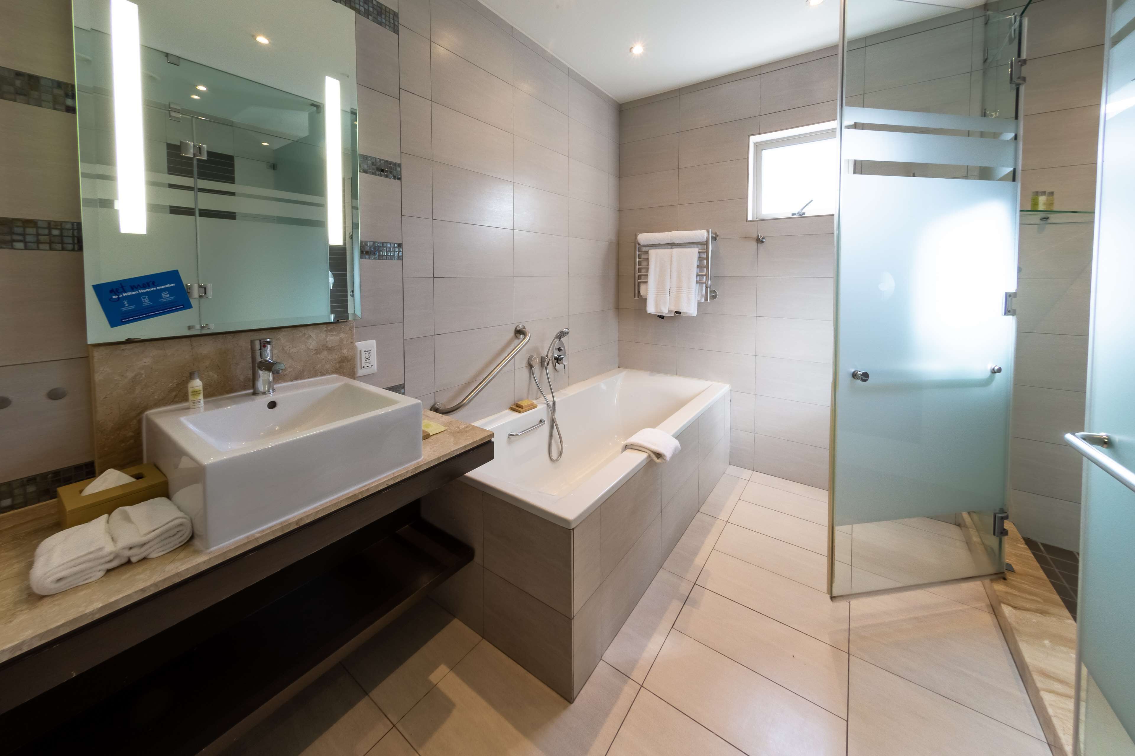 A modern bathroom with a double sink, a bathtub, and a glass shower enclosure.