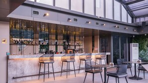 A modern bar area with a glass enclosure, bar stools, and tables with chairs. - Golden Age Hotel Taksim (Istanbul)