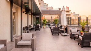 A rooftop terrace with wicker furniture, potted plants, and a view of the cityscape. - Golden Age Hotel Taksim (Istanbul)