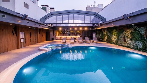 A modern indoor pool area with a glass-enclosed bar and lounge seating. - Golden Age Hotel Taksim (Istanbul)