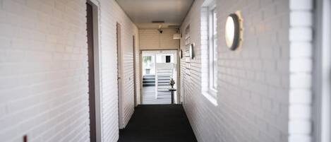 A corridor with white brick walls, a black floor, and a door at the end.